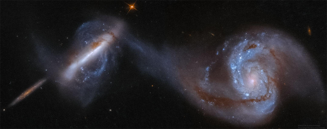 Three large galaxies are shown, the rightmost 
two in collision. The galaxy on the far right is a large
spiral galaxy with one arm connected to an unusual 
polar galaxy on the left. The smaller galaxy on the far
left is thought to be far in the background.
Please see the explanation for more detailed information.