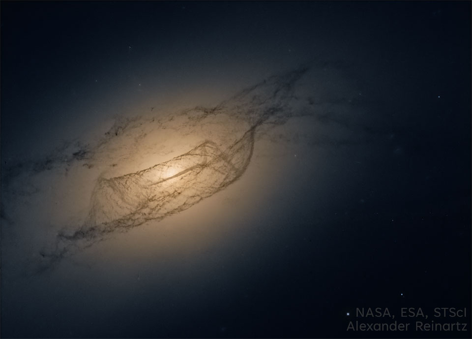 A dark field shows an oblong orange glow with some
dark and complex dust lanes running through.
Please see the explanation for more detailed information.