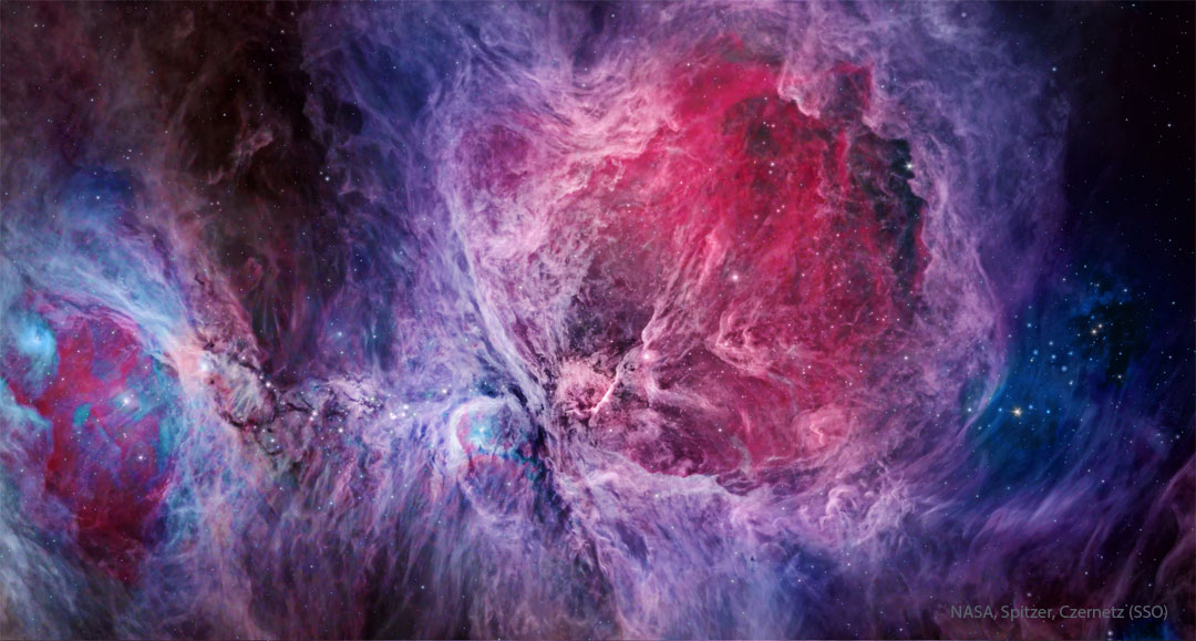 A complex nebula fills the frame that is brightly coloured,
with red being prominent in the image centre and blue being 
most prominent elsewhere. Stars also dot the image. 
Please see the explanation for more detailed information.