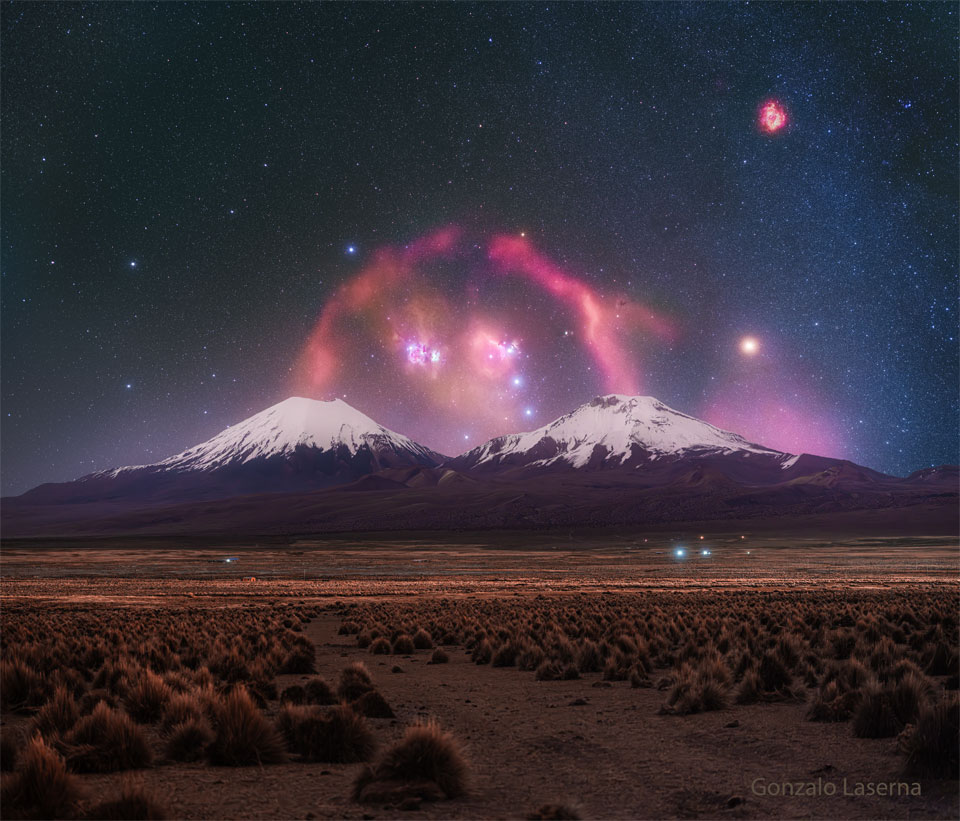 A pair of snow topped volcanoes are seen in the distance.
A background starry sky is seen behind them, with a red filamentary
nebula looping around that appears to connect the two tops 
of the volcanoes. 
Please see the explanation for more detailed information.