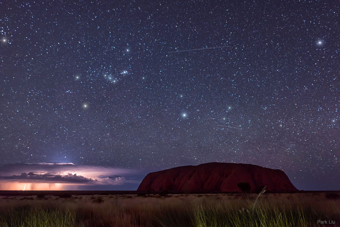 A picture of Uluru rock in Australia in front of lightning and the constellation of Orion. 
Please see the explanation for more detailed information.
