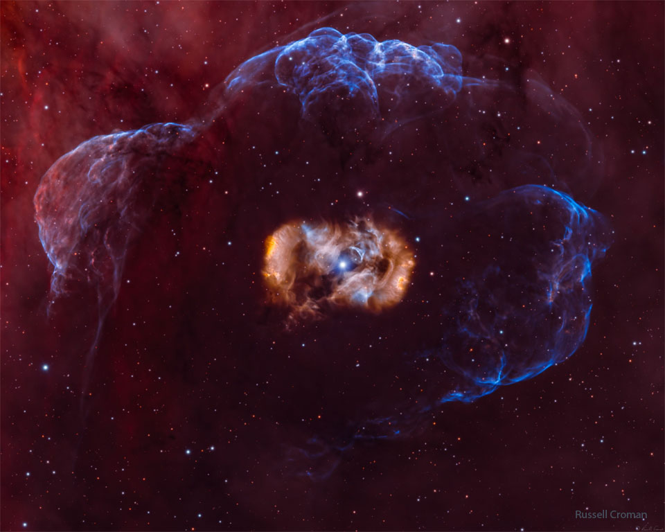 The featured image shows a star inside a symmetric but complex
and multi-coloured nebula which is all surrounded by a faint blue nebula.
Please see the explanation for more detailed information.