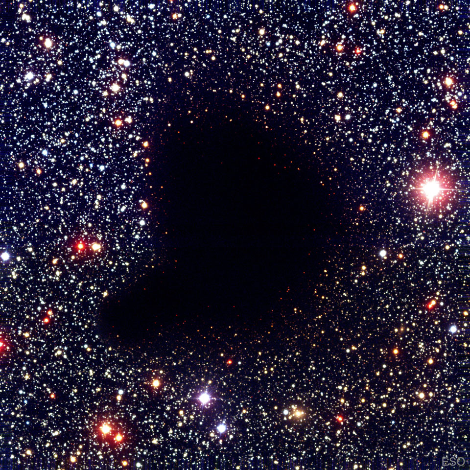 A dark comma-shaped cloud appears in the middle of a dense
field of stars. No stars are visible through the centre of the cloud.
Please see the explanation for more detailed information.