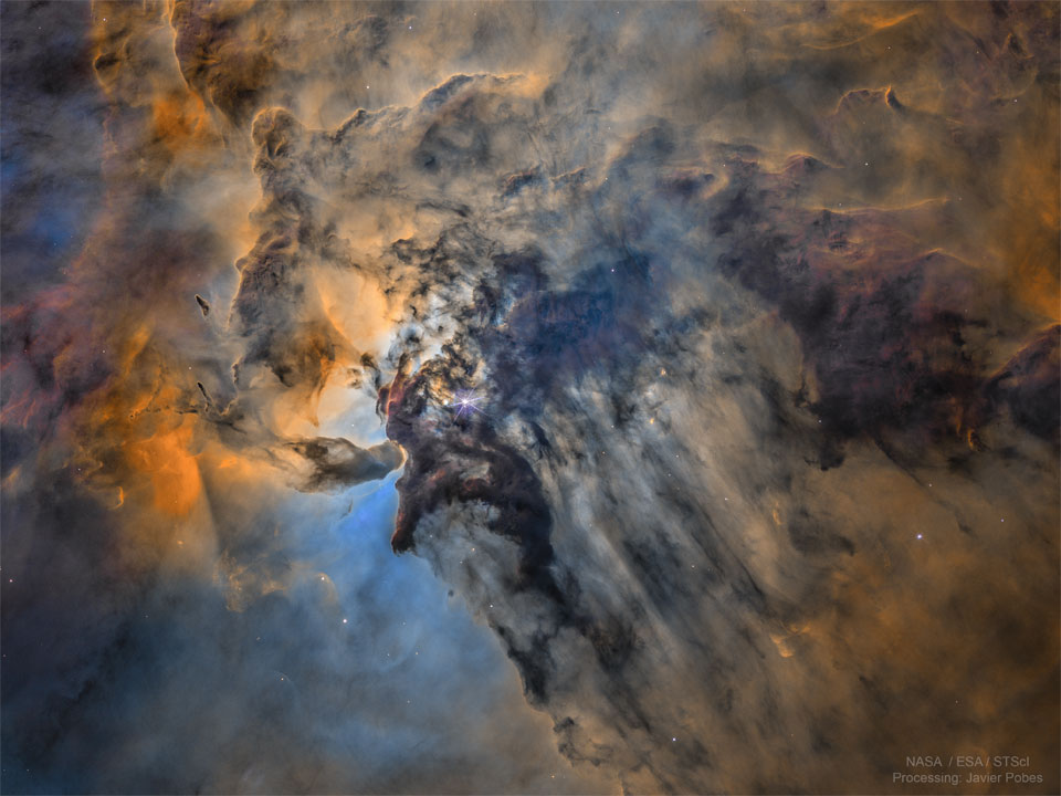 The centre of the Lagoon Nebula is pictured in false colours. 
Toward the centre left, dark dust swirls around glowing gas and bright stars.
Please see the explanation for more detailed information.