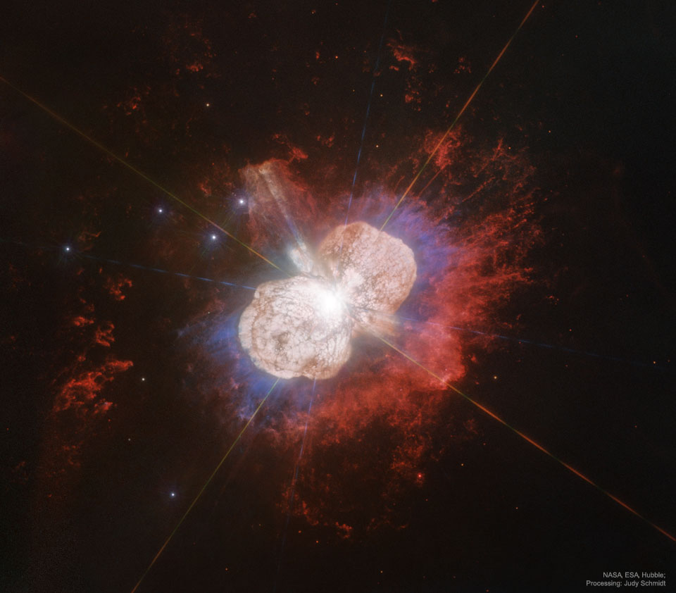 A Hubble image of the gas and dust surrounding the star Eta Carinae 
is shown. The nebula has two distinct light-coloured lobes, surrounded by
red glowing gas. 
Please see the explanation for more detailed information.