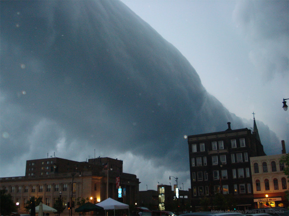 Building in a city are pictured. Above the buildings appears a long
dark cylindrical cloud that goes to the horizon. 
Please see the explanation for more detailed information.